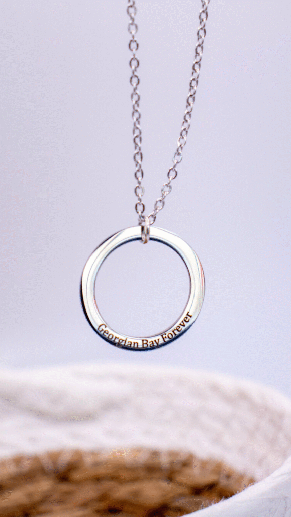 Metallic ring pendant engraved with geographic coordinates: 45° 30' 0.0" N, 81° 00' 0.0" W.