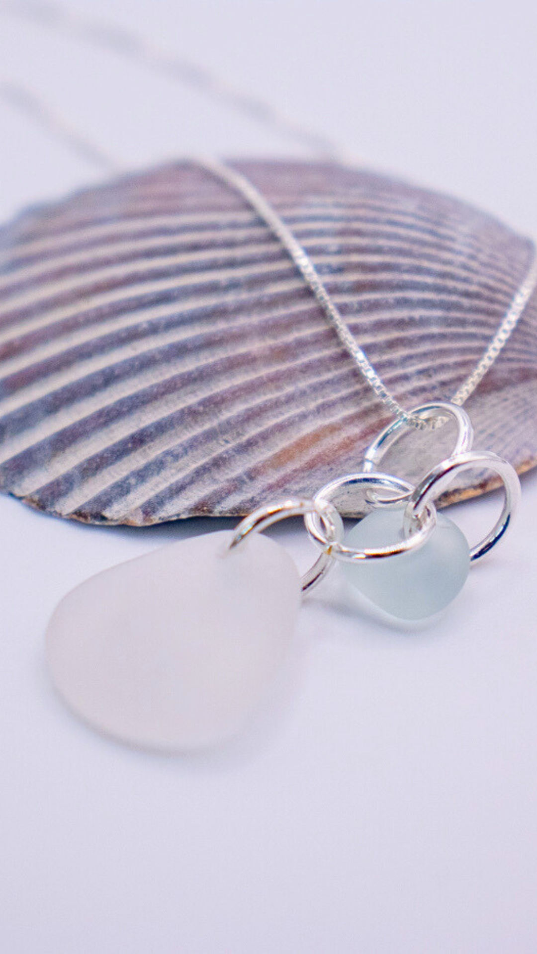 Necklace with a thin silver chain featuring two frosted pendants, one white teardrop-shaped and the other light blue.